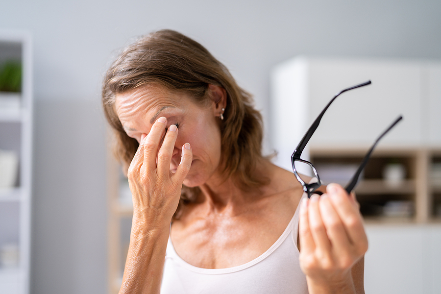 a woman holding glasses and touching her eye