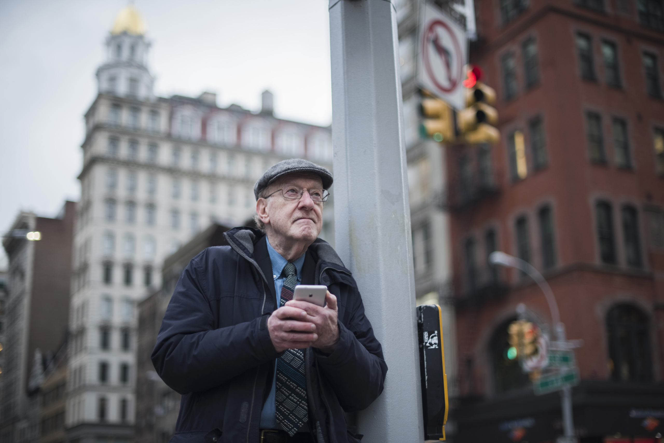 man leaning against lamppost holding smartphone scaled